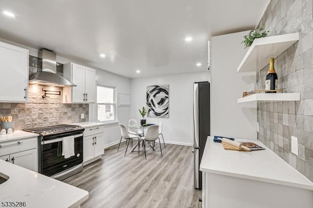 kitchen featuring wall chimney exhaust hood, stainless steel appliances, and white cabinets