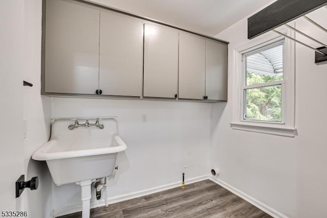 washroom with cabinets, washer hookup, dark hardwood / wood-style flooring, and sink