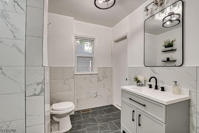 bathroom with tile walls, vanity, and toilet