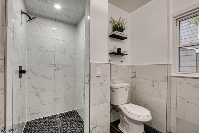 bathroom with tile walls, toilet, and tiled shower