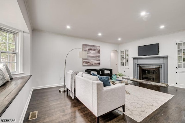 living room featuring dark hardwood / wood-style flooring, a fireplace, and ornamental molding