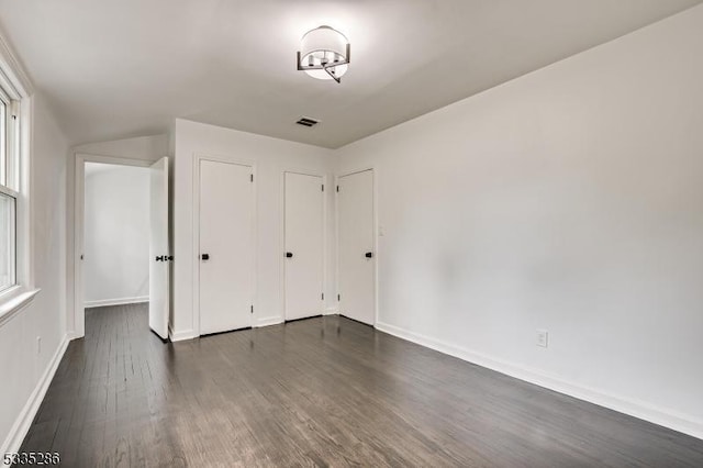 unfurnished bedroom featuring dark hardwood / wood-style floors and two closets