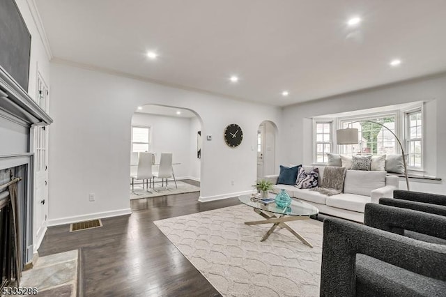 living room featuring crown molding, a high end fireplace, dark hardwood / wood-style floors, and plenty of natural light