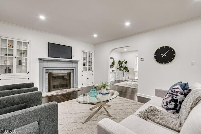 living room with wood-type flooring, a brick fireplace, and ornamental molding