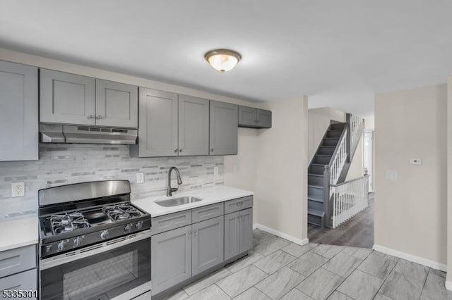 kitchen featuring sink, gas range, gray cabinets, and backsplash