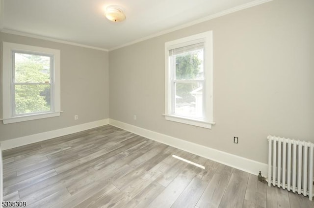 unfurnished room featuring crown molding, a healthy amount of sunlight, radiator, and light hardwood / wood-style flooring