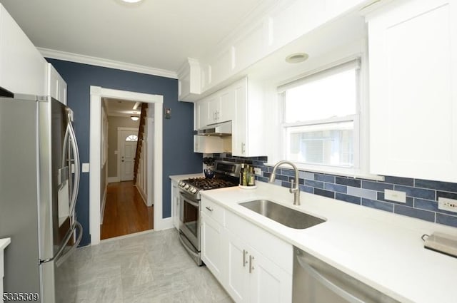 kitchen featuring sink, ornamental molding, stainless steel appliances, and white cabinets