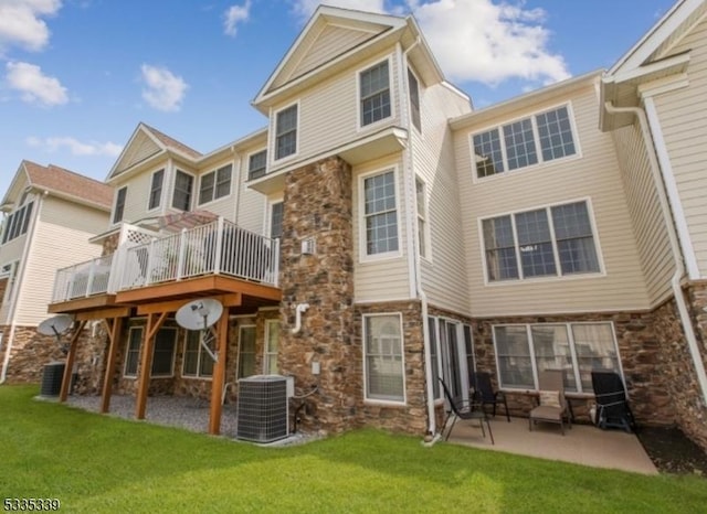 rear view of house with cooling unit, a wooden deck, a patio area, and a lawn