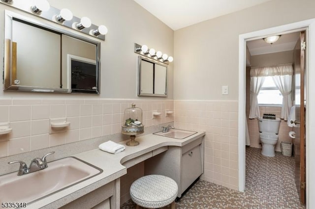 bathroom with tile walls, toilet, vanity, and tile patterned flooring