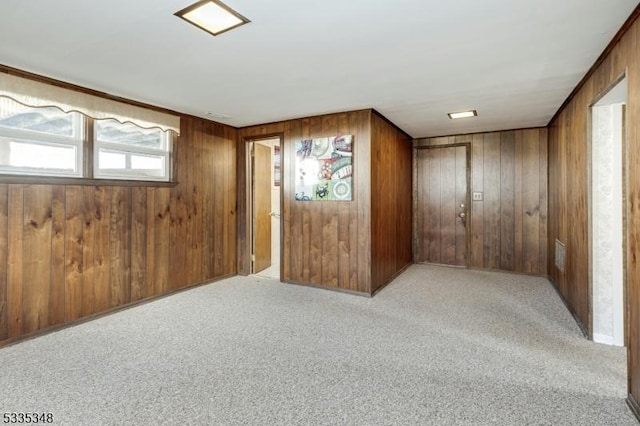 carpeted spare room with wood walls