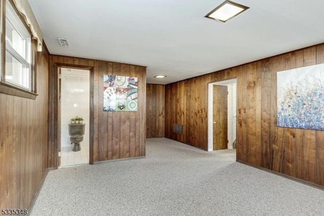 spare room with wood walls and light colored carpet