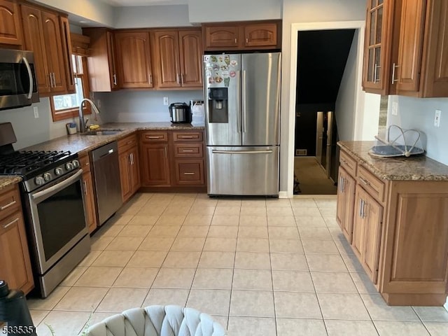 kitchen featuring light tile patterned floors, stainless steel appliances, sink, and stone counters