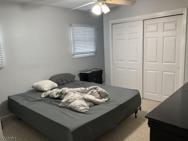 carpeted bedroom with ceiling fan and a closet