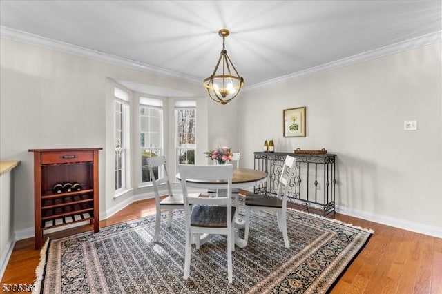 dining space featuring ornamental molding, hardwood / wood-style floors, and a notable chandelier