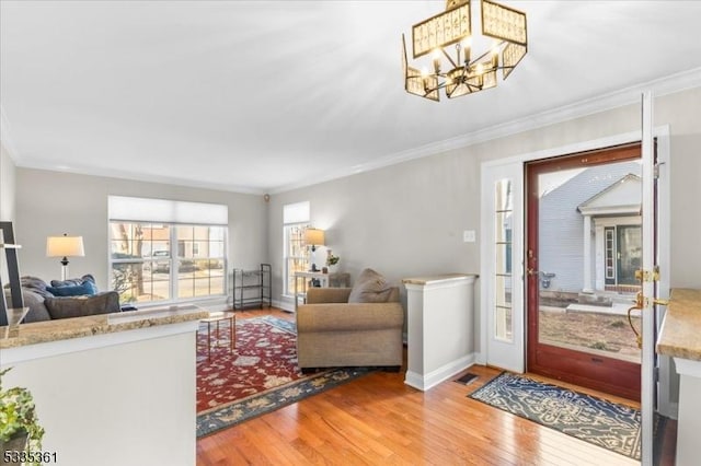 living room featuring crown molding, an inviting chandelier, and light wood-type flooring