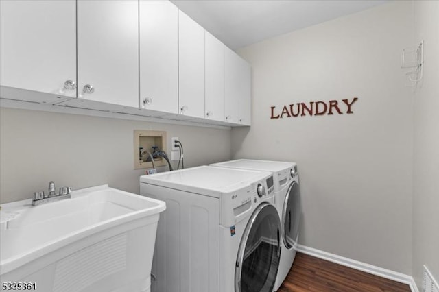 laundry area with dark wood-type flooring, cabinets, sink, and washer and dryer