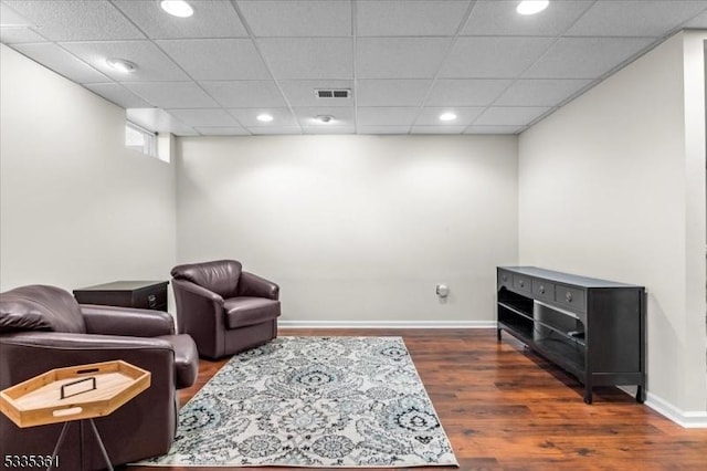 living area featuring dark hardwood / wood-style flooring and a paneled ceiling