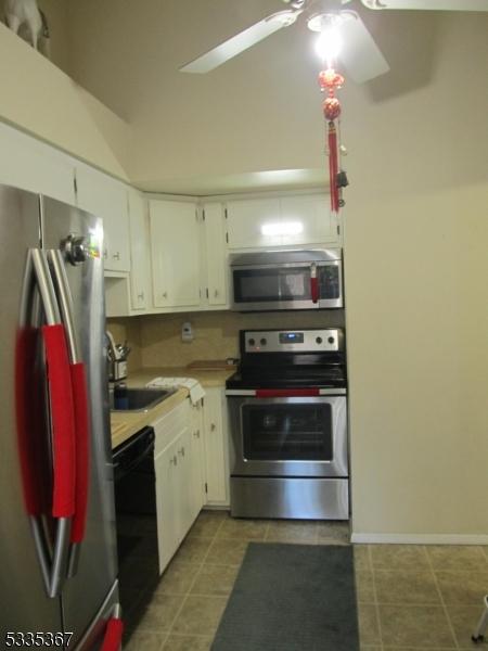 kitchen featuring ceiling fan, appliances with stainless steel finishes, white cabinets, and tile patterned floors