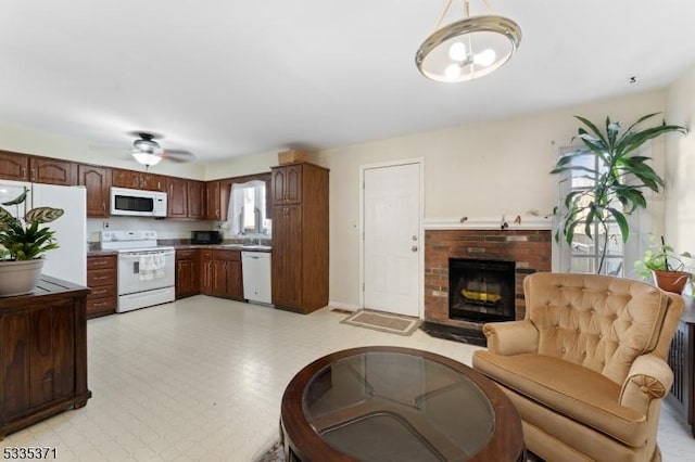 living room featuring a brick fireplace, sink, and ceiling fan