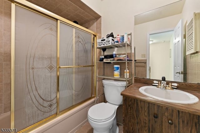 full bathroom featuring vanity, combined bath / shower with glass door, tile walls, and toilet