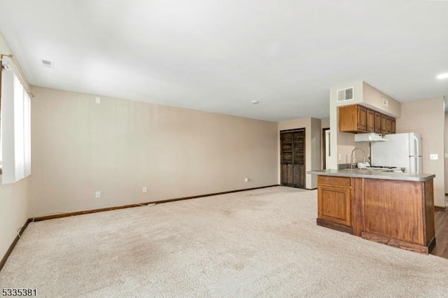 kitchen featuring white fridge, sink, light colored carpet, and kitchen peninsula