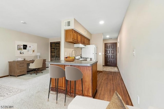 kitchen with white fridge, a kitchen breakfast bar, and kitchen peninsula