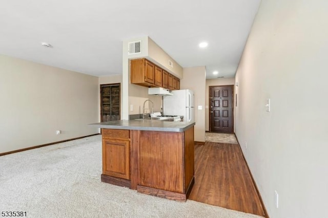 kitchen with white refrigerator, sink, light carpet, and kitchen peninsula