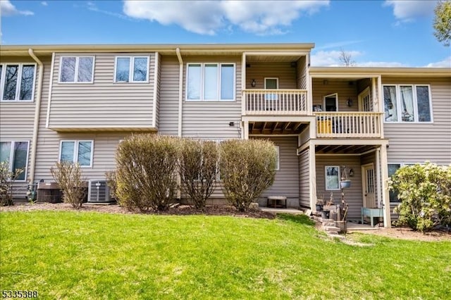 rear view of house featuring a balcony, a yard, and central AC unit