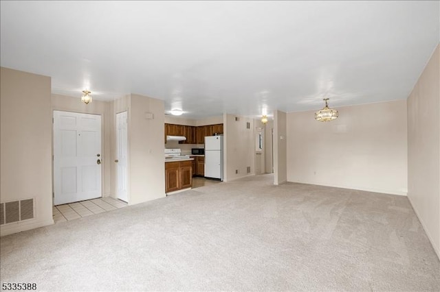 unfurnished living room with a chandelier and light carpet