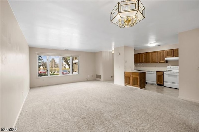 unfurnished living room featuring light colored carpet and a chandelier