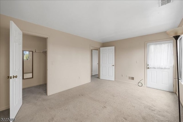 unfurnished bedroom featuring light carpet, a spacious closet, and a closet