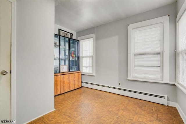 empty room with light parquet floors and a baseboard heating unit