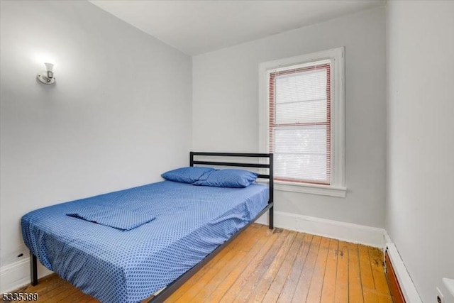 bedroom with wood-type flooring and a baseboard radiator