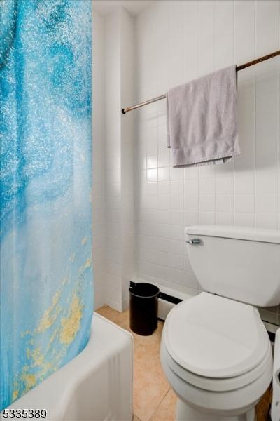 bathroom featuring tile walls, tile patterned floors, toilet, and shower / bath combo