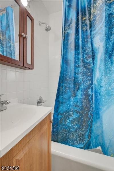 bathroom featuring tasteful backsplash, vanity, and shower / tub combo with curtain