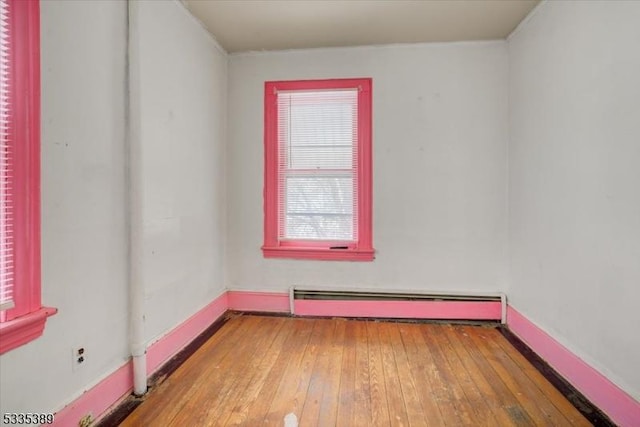 spare room featuring wood-type flooring and a baseboard heating unit