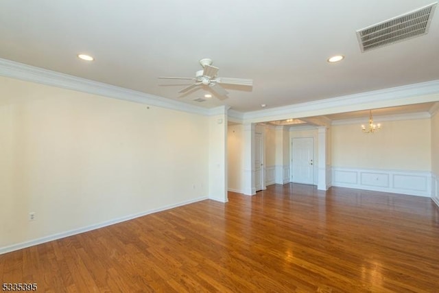 unfurnished room featuring crown molding, wood-type flooring, ceiling fan with notable chandelier, and ornate columns