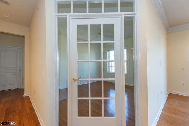 hallway with crown molding, hardwood / wood-style floors, and french doors