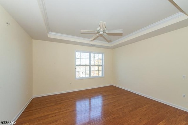 empty room featuring crown molding, a tray ceiling, ceiling fan, and hardwood / wood-style flooring