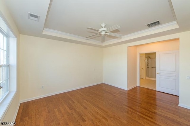 empty room featuring wood-type flooring and a tray ceiling