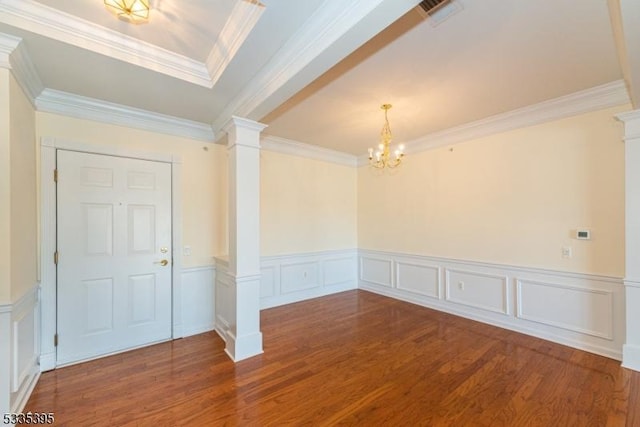 unfurnished room with an inviting chandelier, wood-type flooring, crown molding, and decorative columns