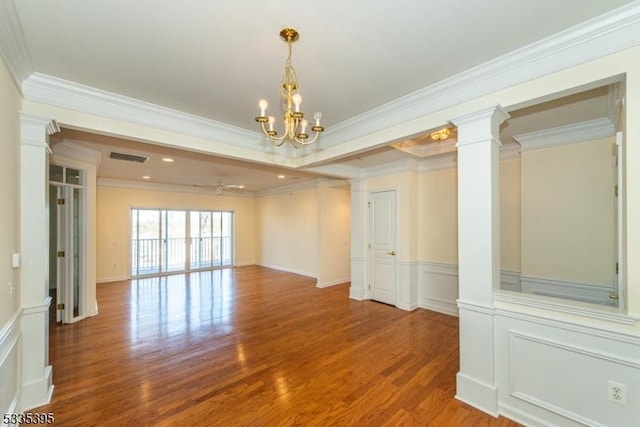 unfurnished room featuring hardwood / wood-style flooring, ornamental molding, decorative columns, and a chandelier