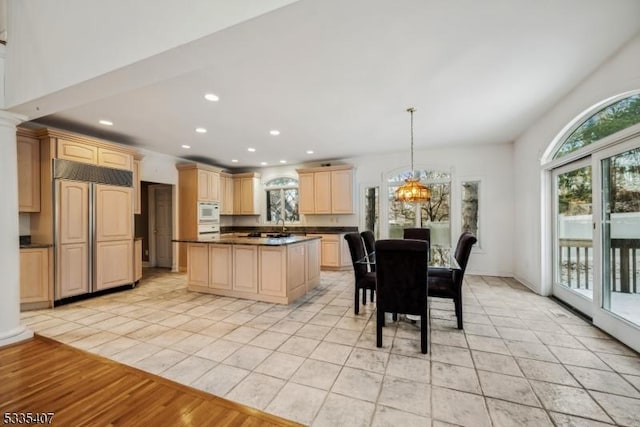 kitchen with hanging light fixtures, paneled built in refrigerator, light brown cabinets, and an inviting chandelier