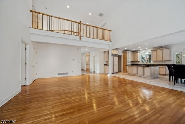 unfurnished living room featuring a towering ceiling and light hardwood / wood-style flooring