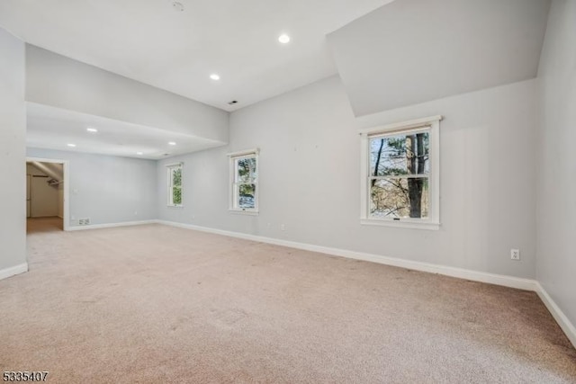 carpeted empty room with a wealth of natural light and vaulted ceiling