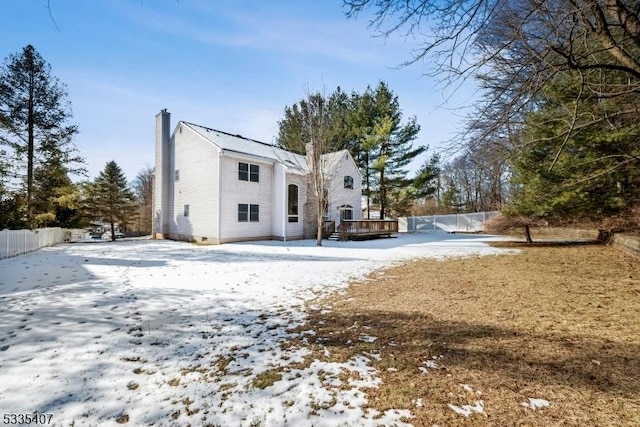 snow covered back of property featuring a deck