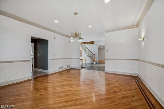 unfurnished room with a notable chandelier, hardwood / wood-style flooring, and ornamental molding