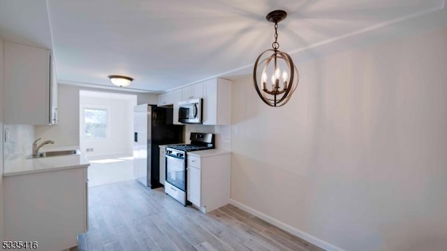 kitchen featuring sink, white cabinetry, decorative light fixtures, appliances with stainless steel finishes, and light hardwood / wood-style floors