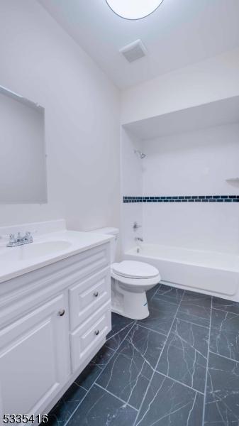 full bathroom with vanity, tiled shower / bath, and toilet