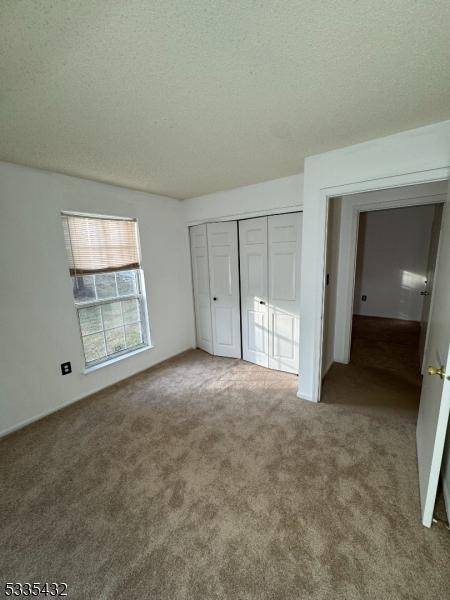 unfurnished bedroom featuring a closet, carpet, and a textured ceiling